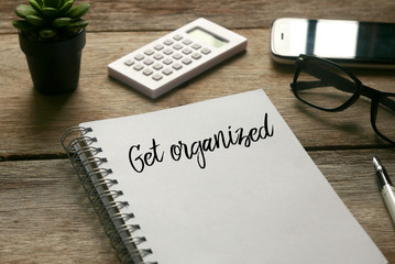 Selective focus of plant,calculator,mobile phone, glasses,pen and notebook written with ' Get Organized ' on wooden background.