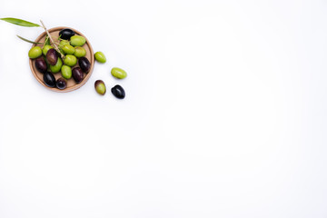 Green and black olives and leaves on white background, top view