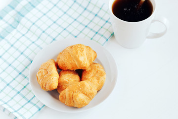 Mini croissants and cup of coffee on white background.