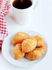Mini croissants and cup of coffee on white background.