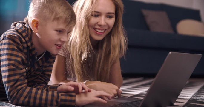 Social distancing and self isolation in quarantine lockdown. A Young woman mother teaches her son and works with him on a laptop at home. Home school education and parents teaching kids at home.