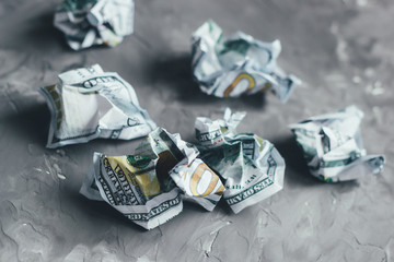 Crumpled dollar banknotes on a gray concrete background.