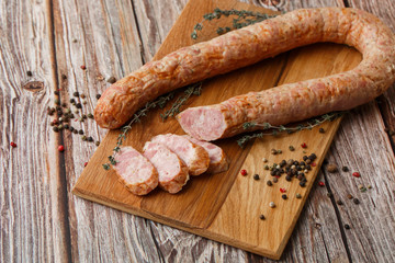 Industrial manufacture of sausages. Smoked homemade sausage sliced spices pepper on cutting board. wooden background rustic style retro vintage. natural product from organic farm.