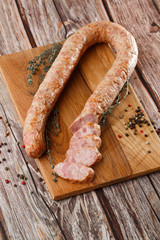 Industrial manufacture of sausages. Smoked homemade sausage sliced spices pepper on cutting board. wooden background rustic style retro vintage. natural product from organic farm.