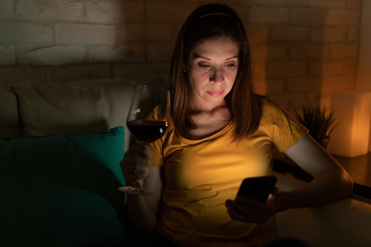 Woman drinking wine and looking at a smartphone