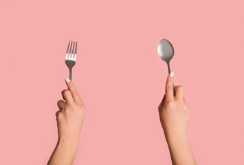 Closeup of unrecognizable girl holding spoon and fork on pink background