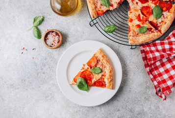 Pepperoni pizza slice on plate on light gray background. Traditional Italian fastfood. With red white checkered towel.