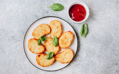 Hash brown or potato pancakes on plate with catsup on light gray background