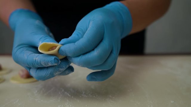 Making of meat dumpling at home close up. Female hands make dumplings. Close up of making dumpling food. Homemade food. Hand made meat dumpling. Meat ball on a piece of dough, cooking pelmeni, close