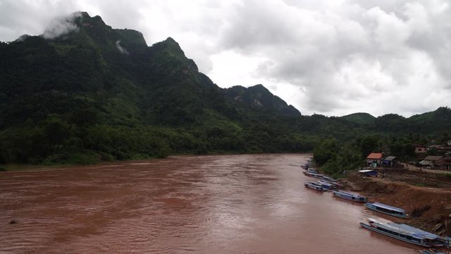 R&iacute;o profundo con barcas y monta&ntilde;as en un d&iacute;a nublado