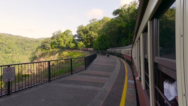 Kuranda Scenic Railway Train. Tourist train journey across rainforest and jungles in Cairns Australia. View of train, train tracks, passenger seats, interior, skyrail, bridge, mountains and landscape.