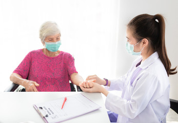 asian doctor use hand screening vital sign of old asian patient , doctor treatment patient in hospital, elderly health check up , they wear surgical mask