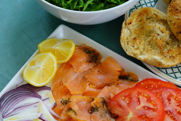 Platter of gravlax salmon slices with tomatoes, onion, cheese, salad and toasted bagels