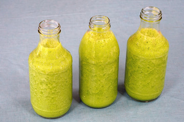 Glass bottles filled with healthy fresh kale and ginger green smoothie