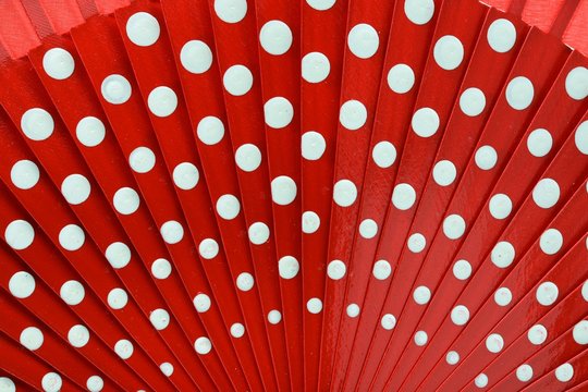 Detalle de un abanico de madera pintado de rojo con lunares blancos