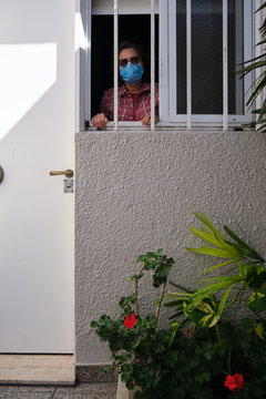 adult woman with a face mask looking out of the windows