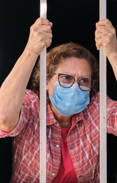 adult woman with a face mask looking out of the windows