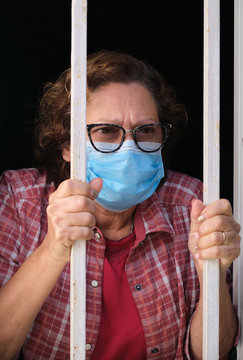 adult woman with a face mask looking out of the windows