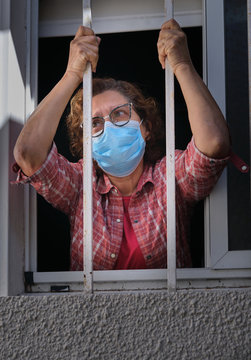 adult woman with a face mask looking out of the windows