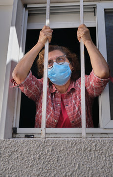 adult woman with a face mask looking out of the windows