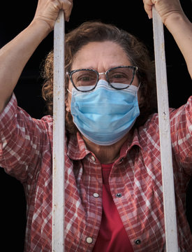 adult woman with a face mask looking out of the windows