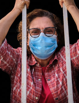 adult woman with a face mask looking out of the windows