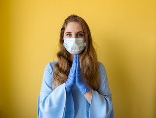 a young beautiful woman with long hair wearing a medical mask and protective disposable gloves on a bright yellow background. Epidemic and quarantine due to coronavirus, self-isolation and treatment