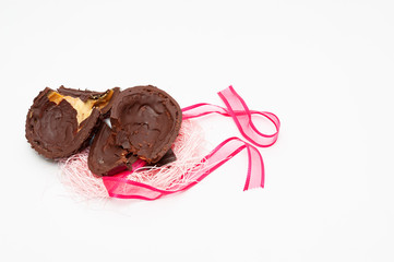Homemade broken chocolate egg with red ribbon. Celebration of Easter, Mother's Day and Valentine's Day. Isolated on white background. Copy space.