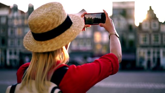 Reverse effect of female traveller taking photos on modern smartphone camera with high resolution, woman tourist with backpack photographing architect buildings using cellular phone outdoors in travel