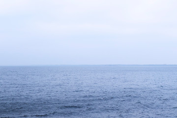 Blue sea water turns into a blue sky, foggy. The skyline is clearly visible in the photo.