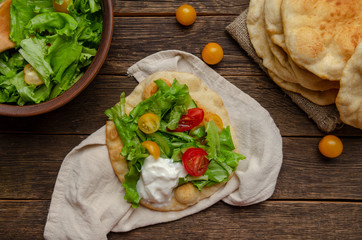 Navajo fried bread with green salad and yougurt on wooden
