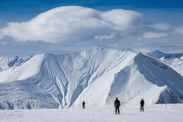 
Small people on the background of a large massive mountain and clouds above it in a ski resort