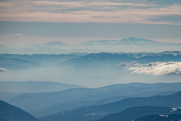 Caucasian mountains in layers in a beautiful foggy haze. 
Landscape