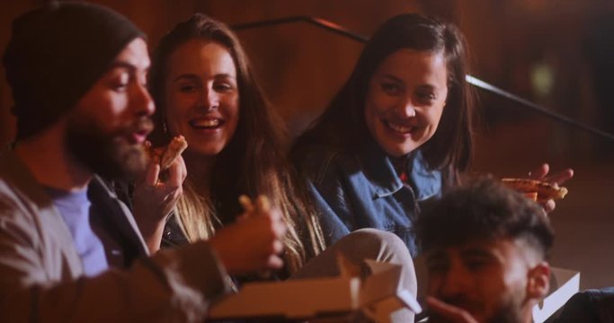 Multi-ethnic group of young friends eating take-away pizza