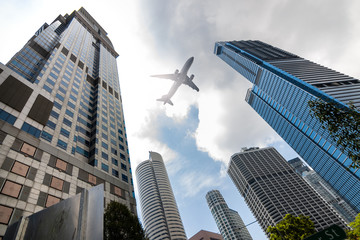 Obraz na płótnie Canvas Air plane flying low over highrise office buildings in downtown of Singapore City