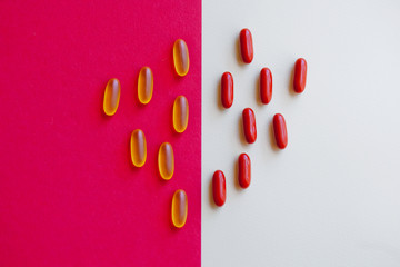Yellow and red capsules of tablets or vitamins on a colored background top view