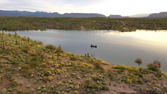 Flying over a lake with a man in his fishing boat enjoying the morning light at Lake Pleasant in Arizona.