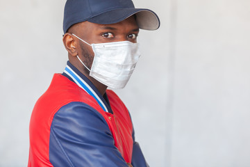 Fototapeta na wymiar Close up photo of handsome african man in a cap and casual clothes wearing medical mask shocked with coronavirus 2019 danger