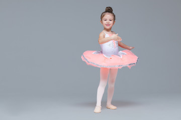Cute adorable ballerina little girl in pink tutu dance practices ballet dancing