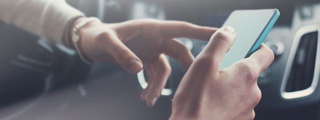 Close-up of woman using mobile phone inside the car. Wide screen, panoramic