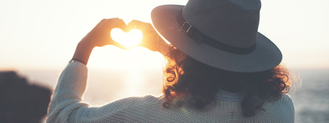 Young traveling female in hat enjoing the adventure, woman hipster making heart symbol with hands....
