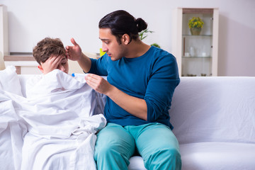Fototapeta premium Young father caring for sick son