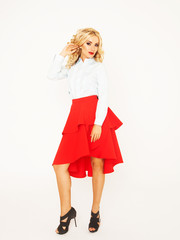 Blond fashion model with luxury hair and red skirt in studio over white background