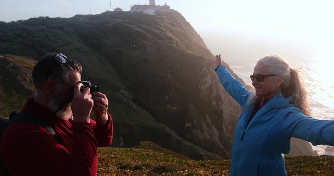 Close up senior man taking picture of woman on cliff