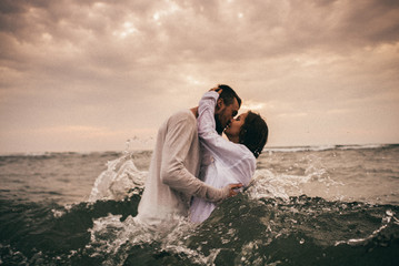 
Happy lovers have a cheerful vibes on sea beach at sunset 
