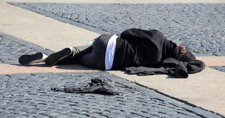 A man sleeps on the sidewalk cobblestone