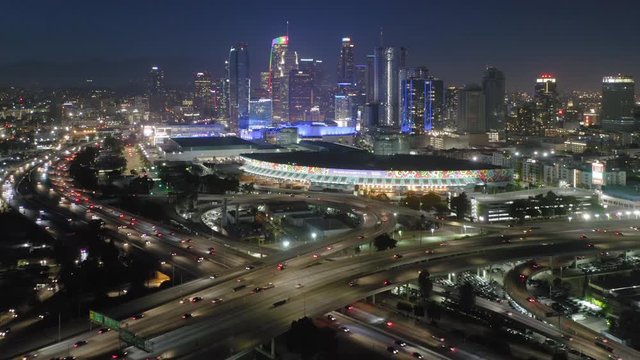 Los Angeles. Downtown. 2019. Aerial view over the big modern city at night. Beautiful night illumination of buildings and roads. Heavy traffic along multi-level freeway. 4K