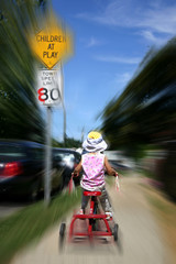 Child on tricycle zooming down sidewalk.