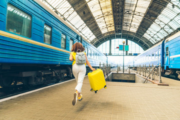 woman running by railway station with bags late for train
