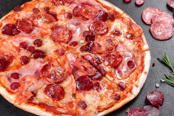 Pepperoni pizza with mozzarella cheese, salami, tomatoes, pepper and spices